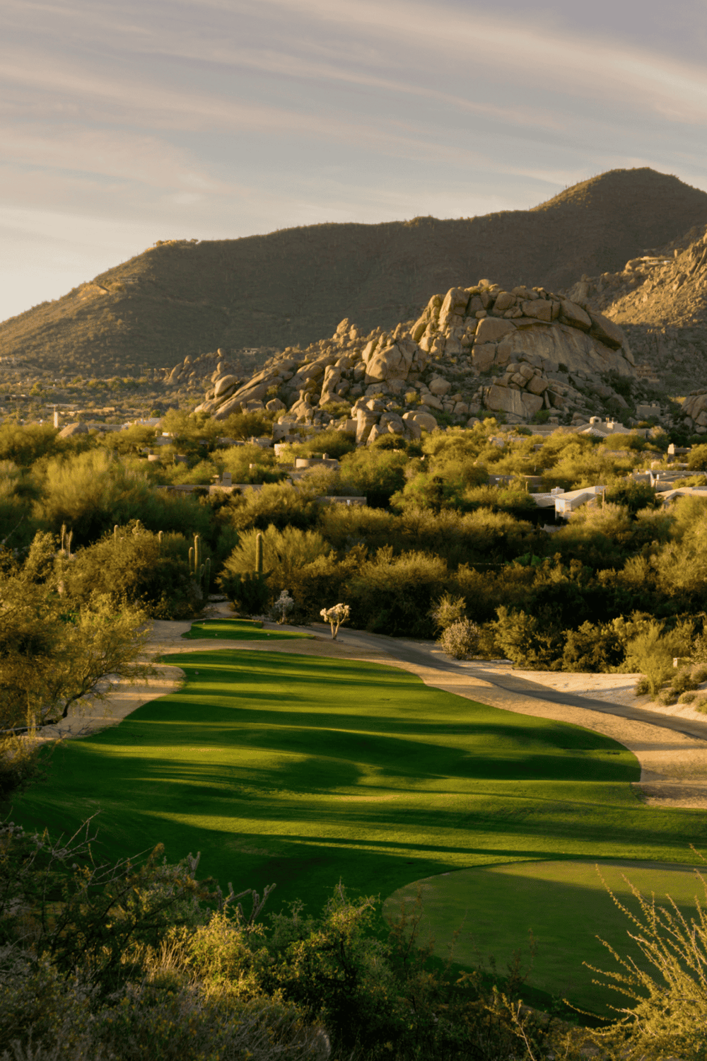 Vibrant golf course nestled in desert mountains with lush green fairways and scenic natural surroundings.
