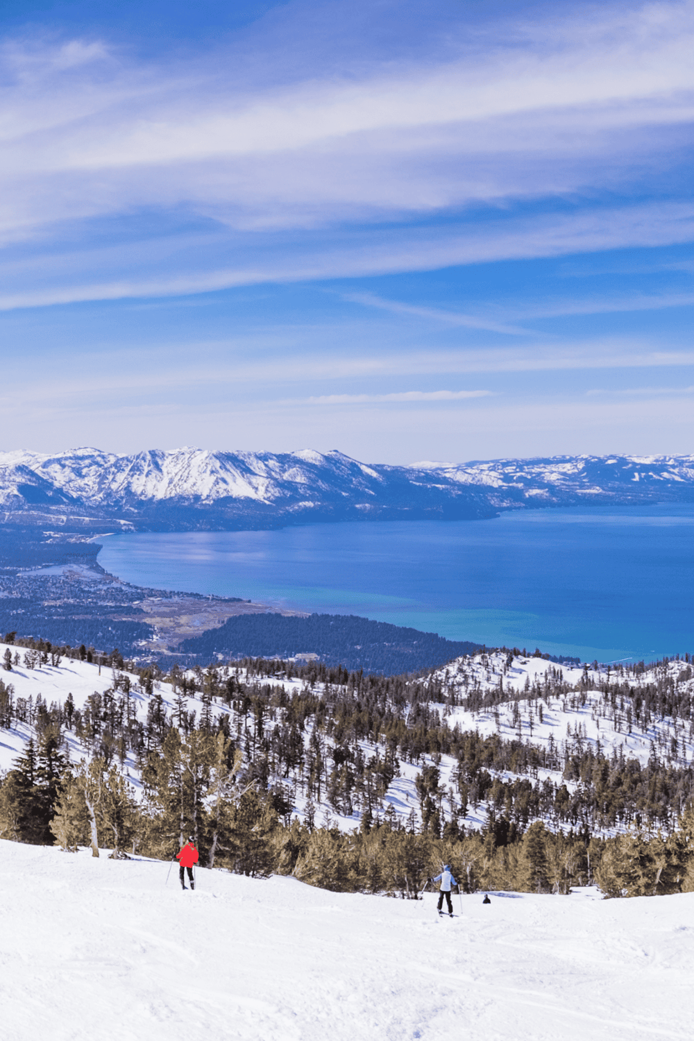 Snowy mountain landscape with skiers and a lake, ideal for outdoor adventures and travel planning.