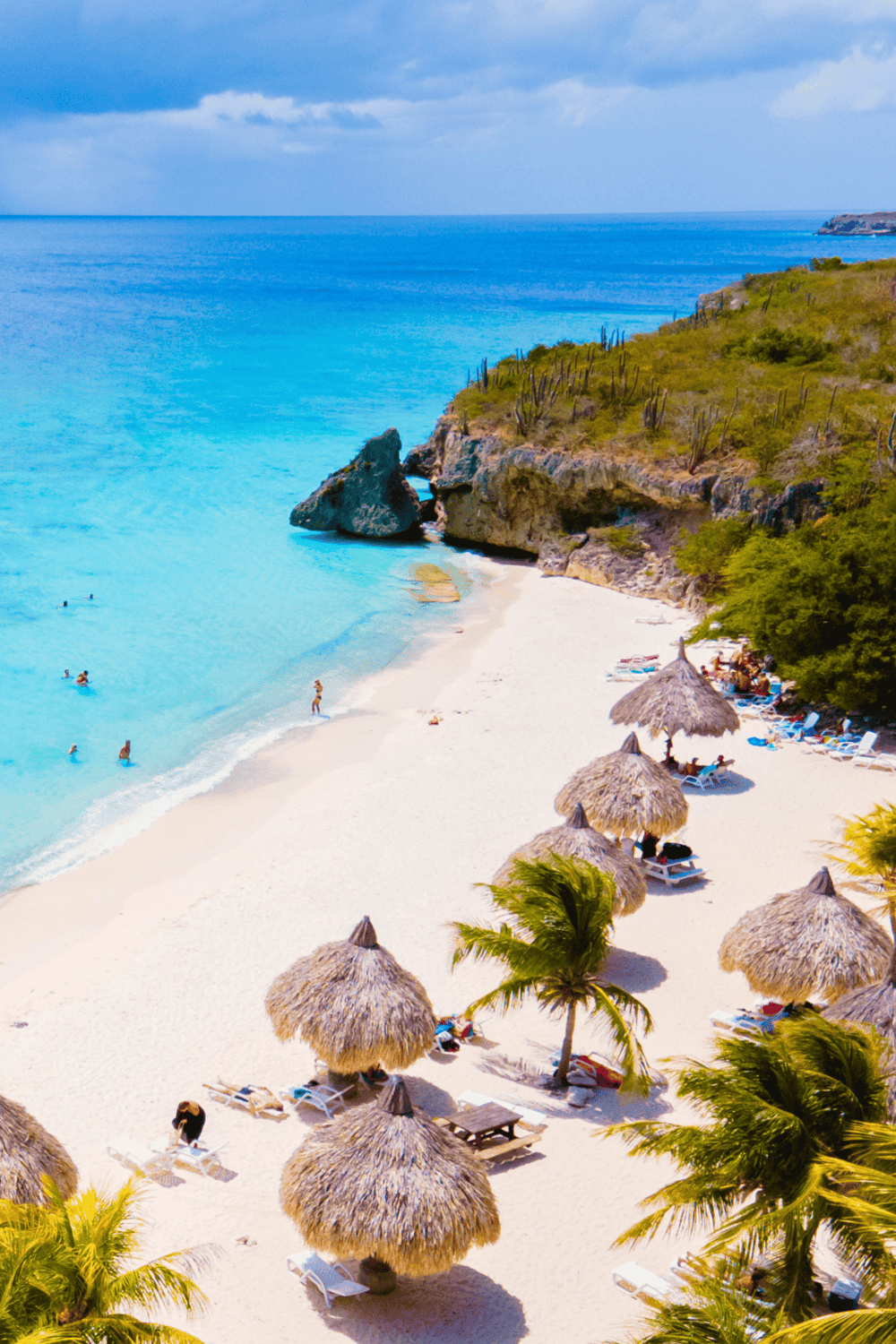Turquoise beach with thatched umbrellas, cove, and ocean view, perfect for vacation and relaxation.