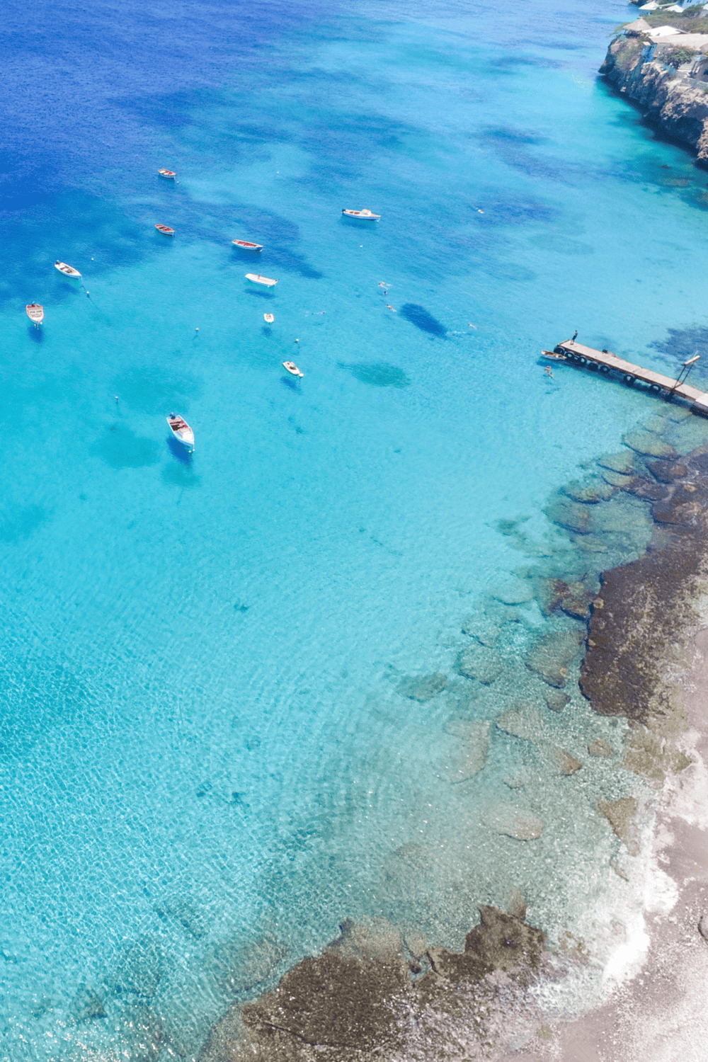 1. Turquoise ocean with boats and rocky shoreline at QuestForDirections destination.