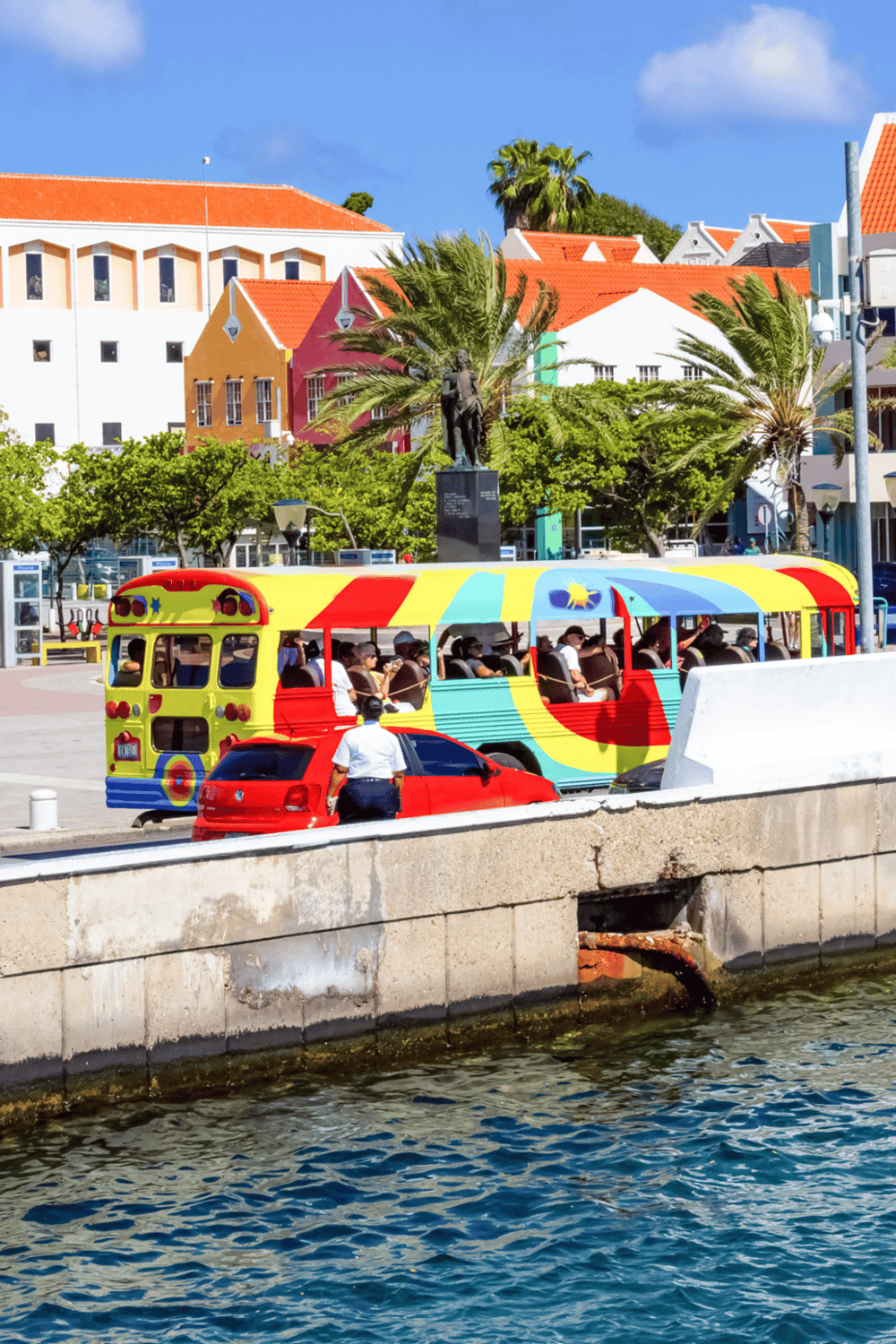 Colorful trolley in Key West with vibrant buildings and palm trees in the background.