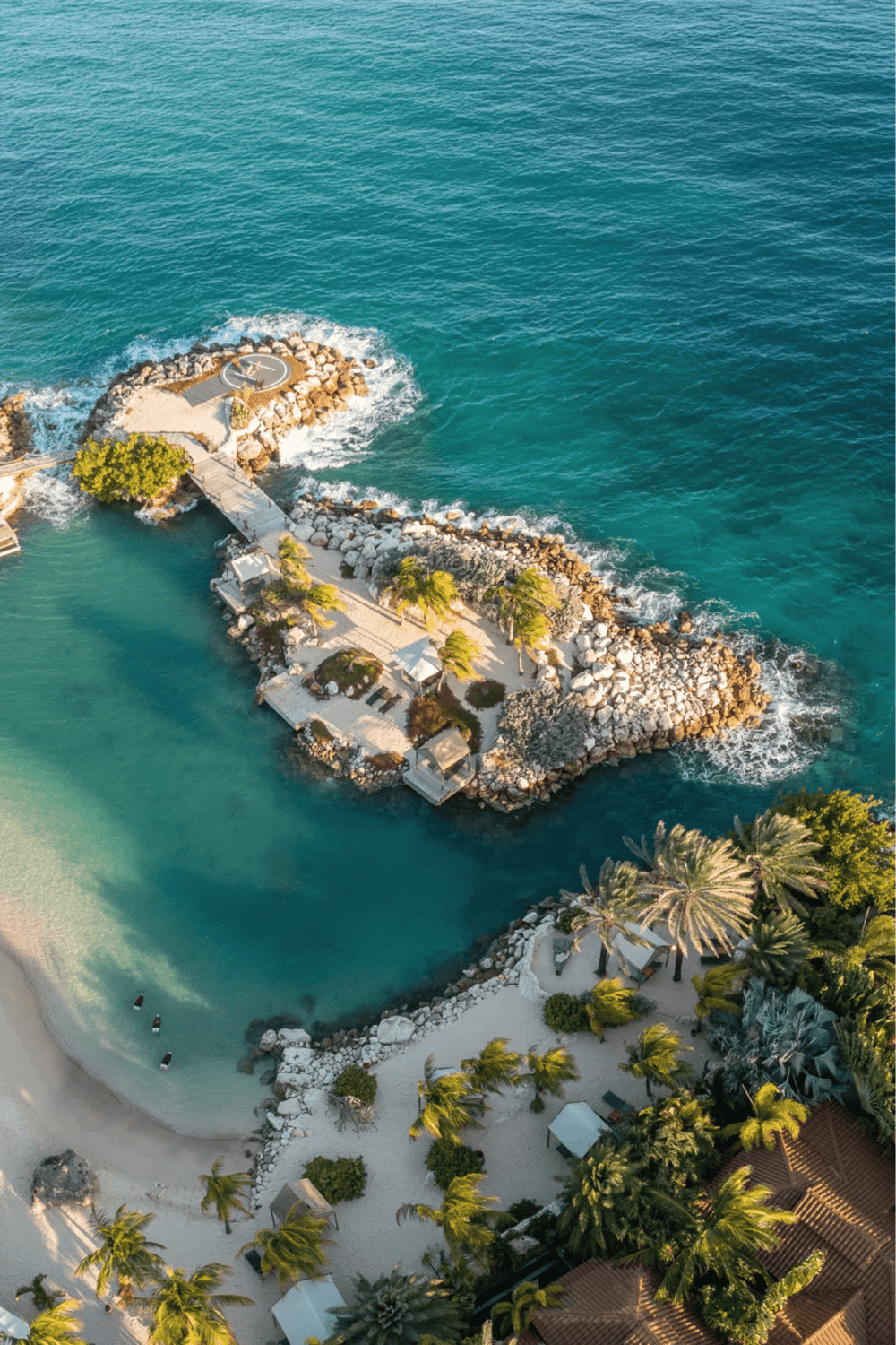 Seaside dock with boat and rocky shoreline, tropical setting, clear turquoise waters, relaxing coastal scenery.