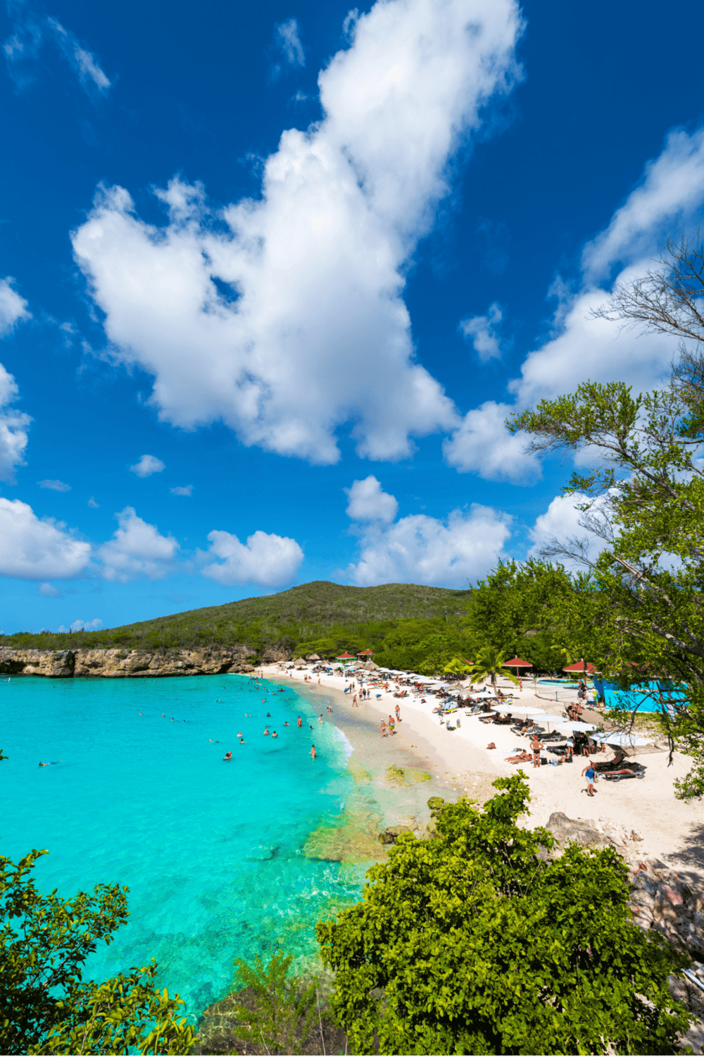Stunning tropical beach with turquoise waters, white sand, and lush green surroundings.
