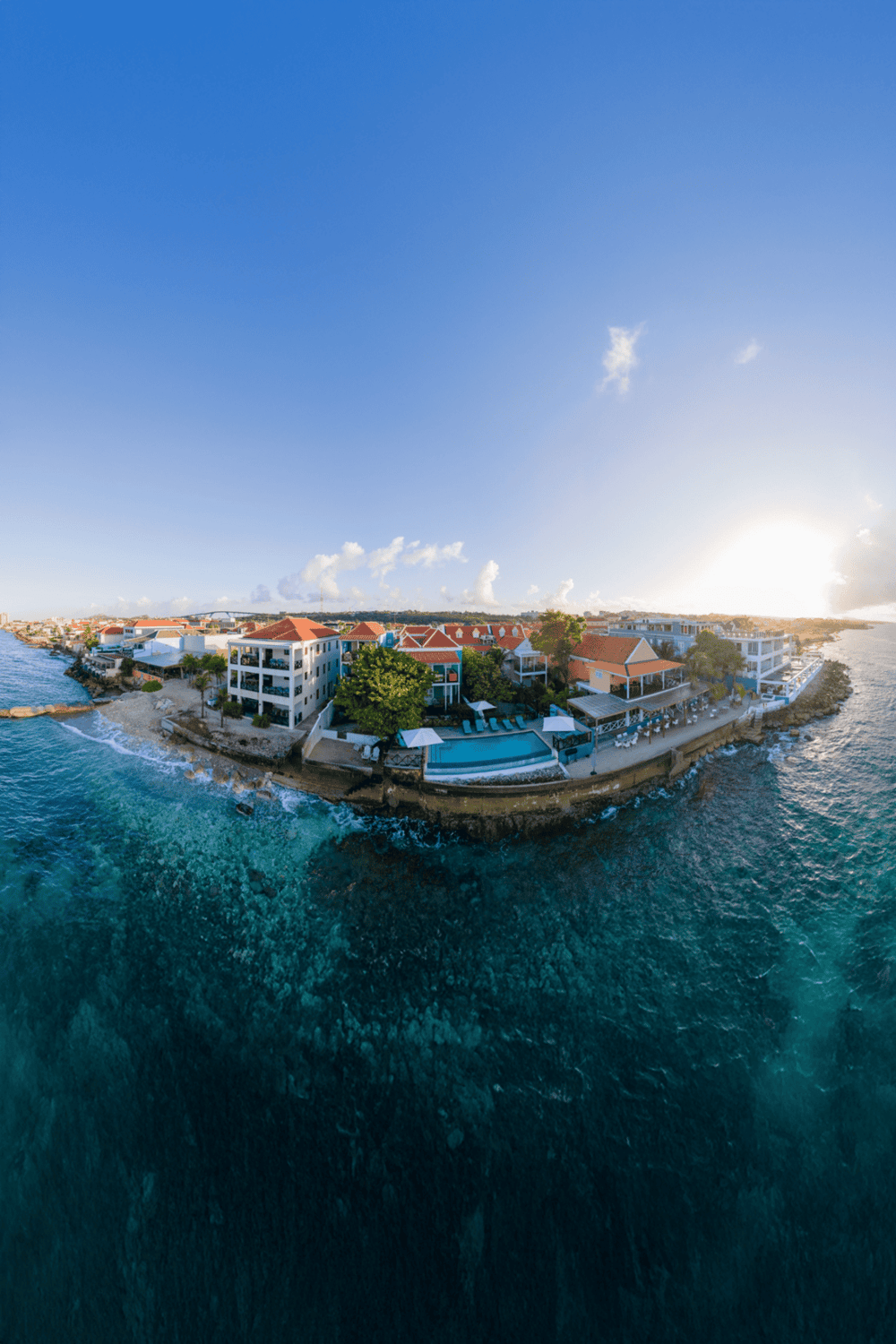 Beachfront luxury resort with pool and ocean views at sunset.
