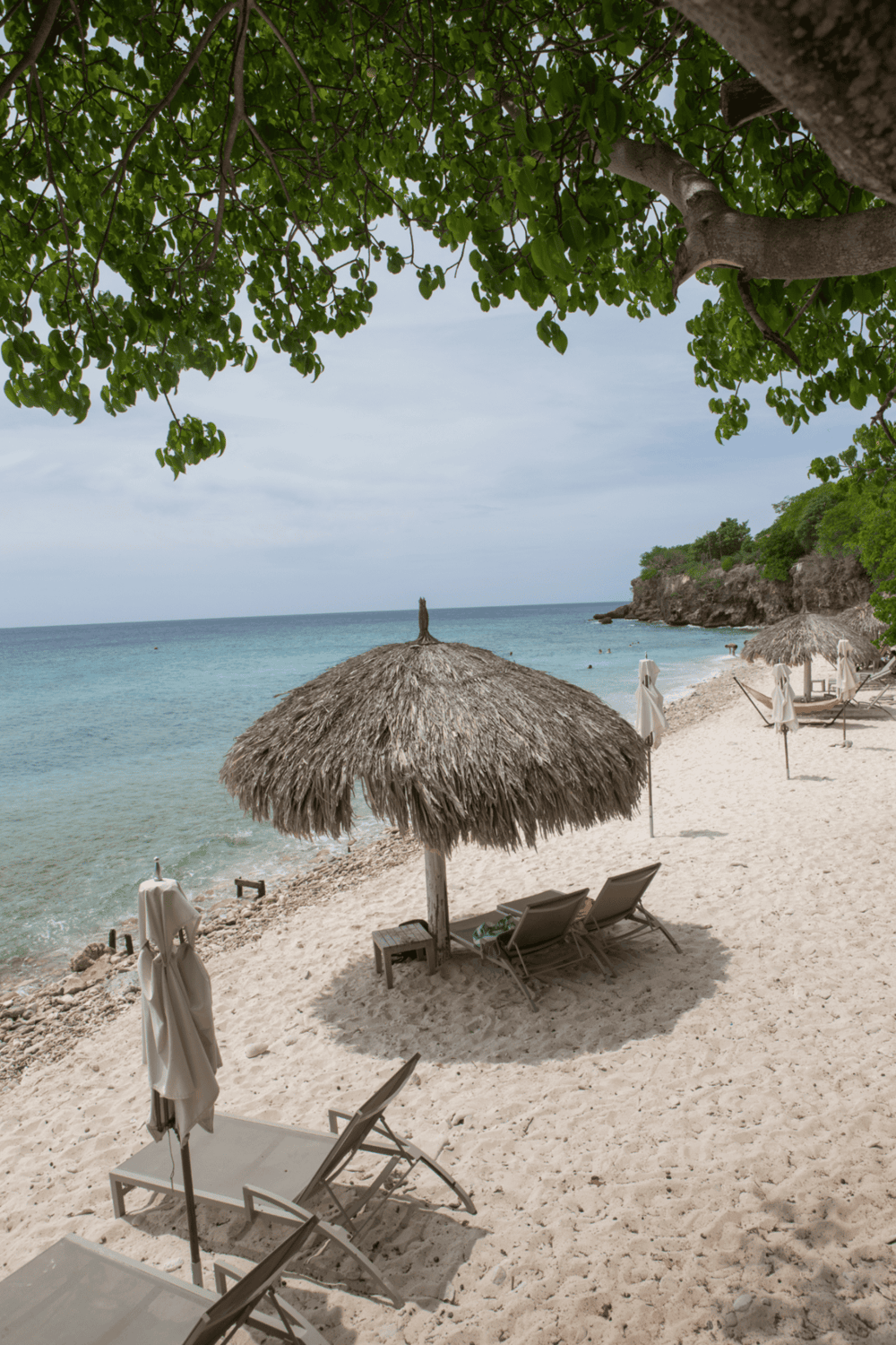 Relaxing beach scene with umbrellas, lounge chairs, and turquoise water, perfect for tropical vacation and travel guides.