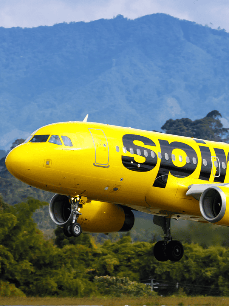 Plane landing with Spirit Airlines branding at an airport.