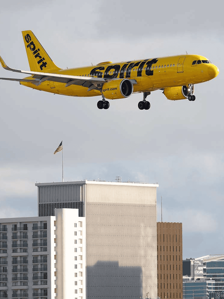 1. Low-flying Spirit Airlines jet over city buildings.
