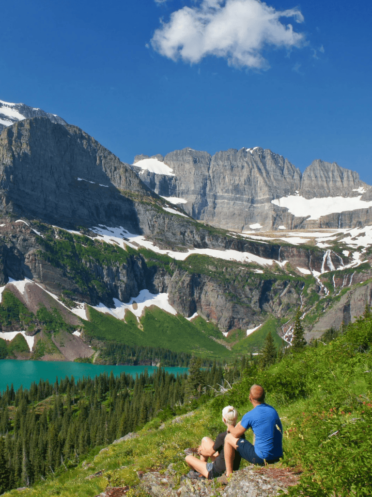 Majestic mountain landscape with hikers enjoying nature and scenic views of snow-capped peaks and pristine lake in Montana.