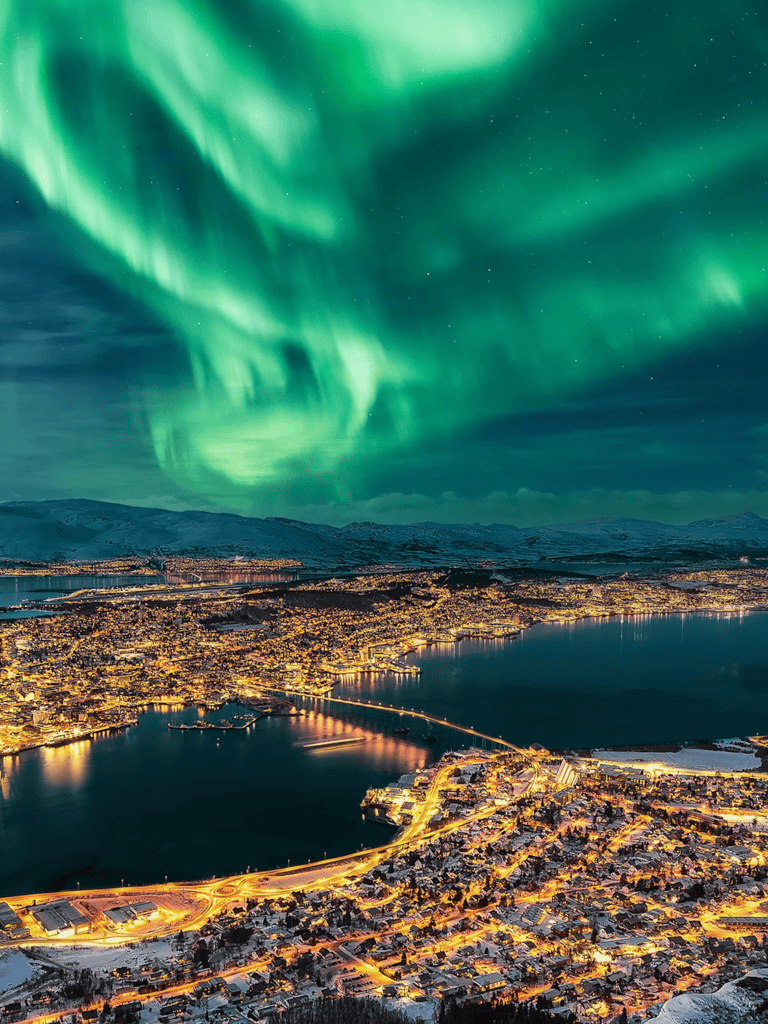 Aurora borealis over cityscape at night, scenic northern lights travel destination.