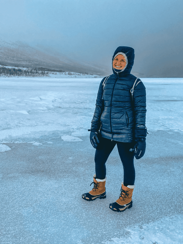 Cold weather adventure woman on frozen lake, winter outdoor explorer, snow hiking gear.