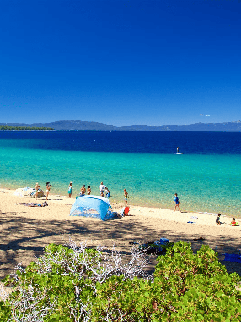 Stunning beach scene with turquoise waters, sandy shore, and people enjoying sunny day outdoors on vacation.