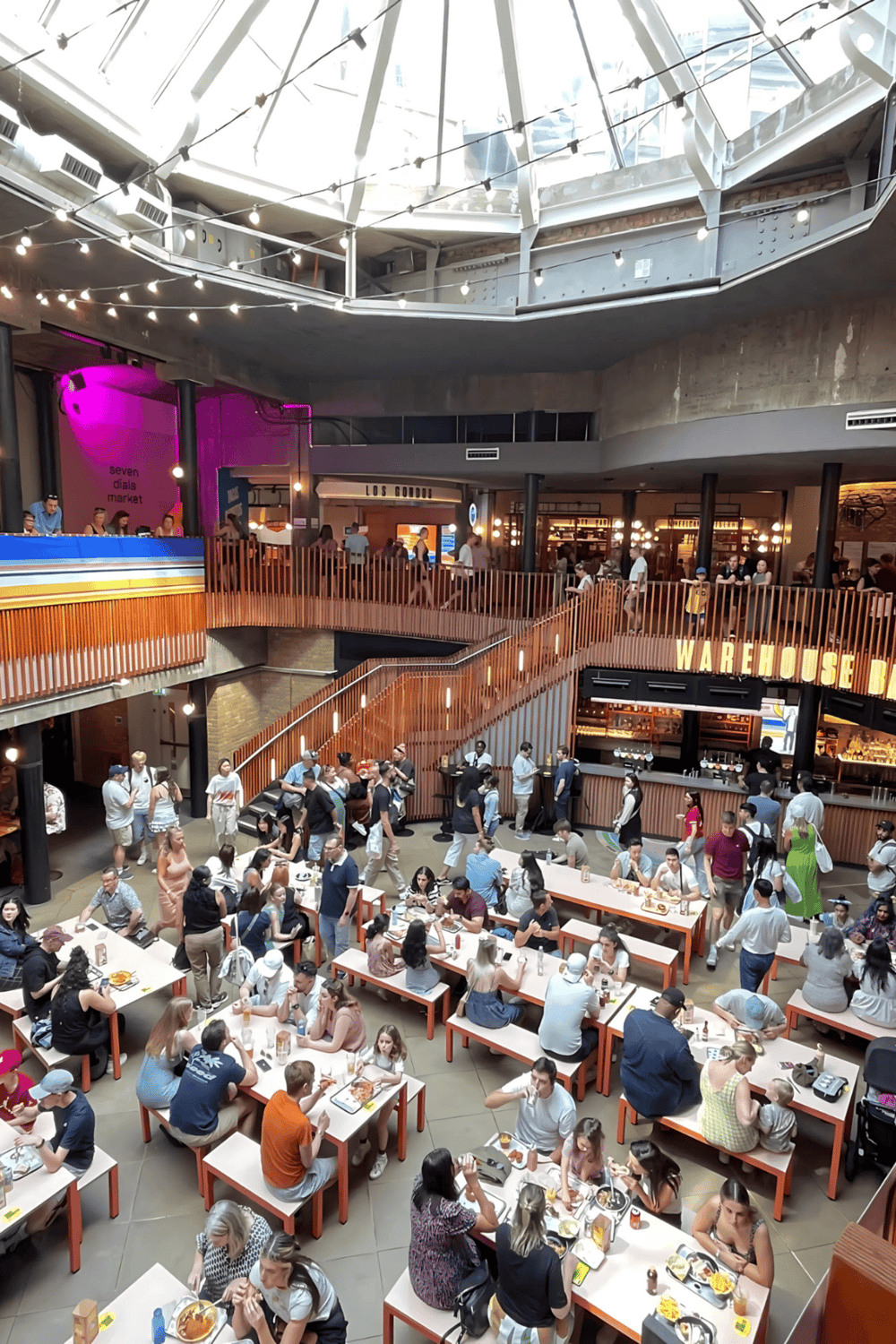 1. Bright indoor food hall with multiple dining levels, bustling crowds, and modern industrial design.