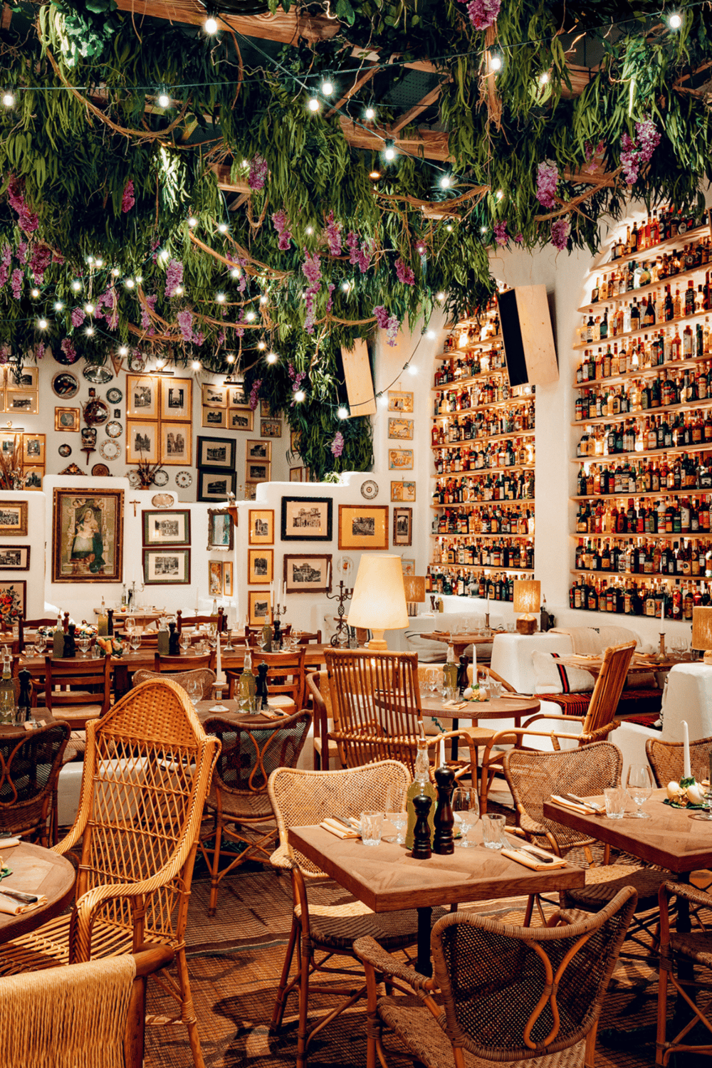 Cozy restaurant interior with wooden furniture, extensive liquor shelf, and vibrant ceiling décor and lighting for an inviting dining experience.