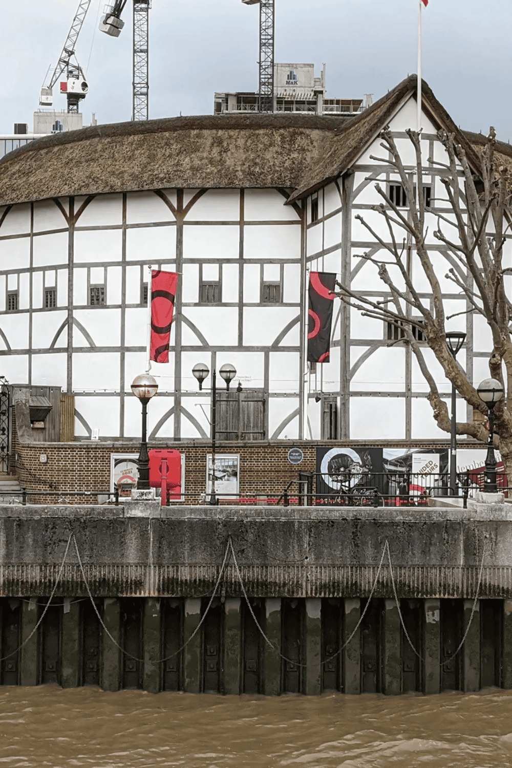 1. Half-timbered house by the river with flags and vintage decor, in a historic waterfront setting.