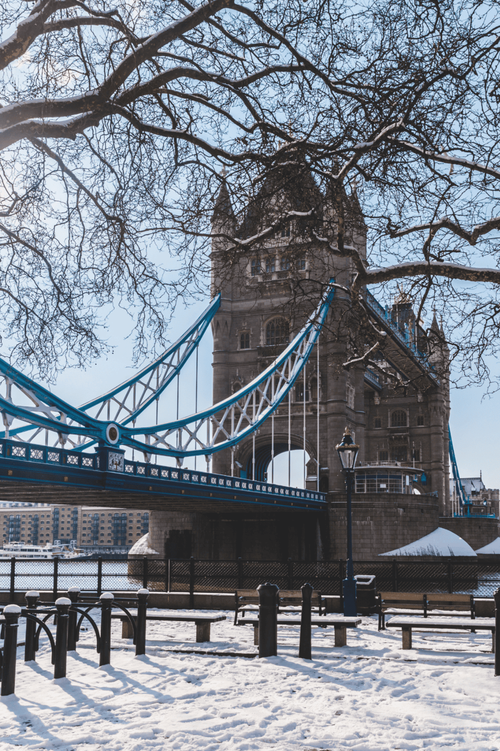 Snow-covered Tower Bridge in London, iconic landmark with suspension design, winter scenery, and historic architecture.