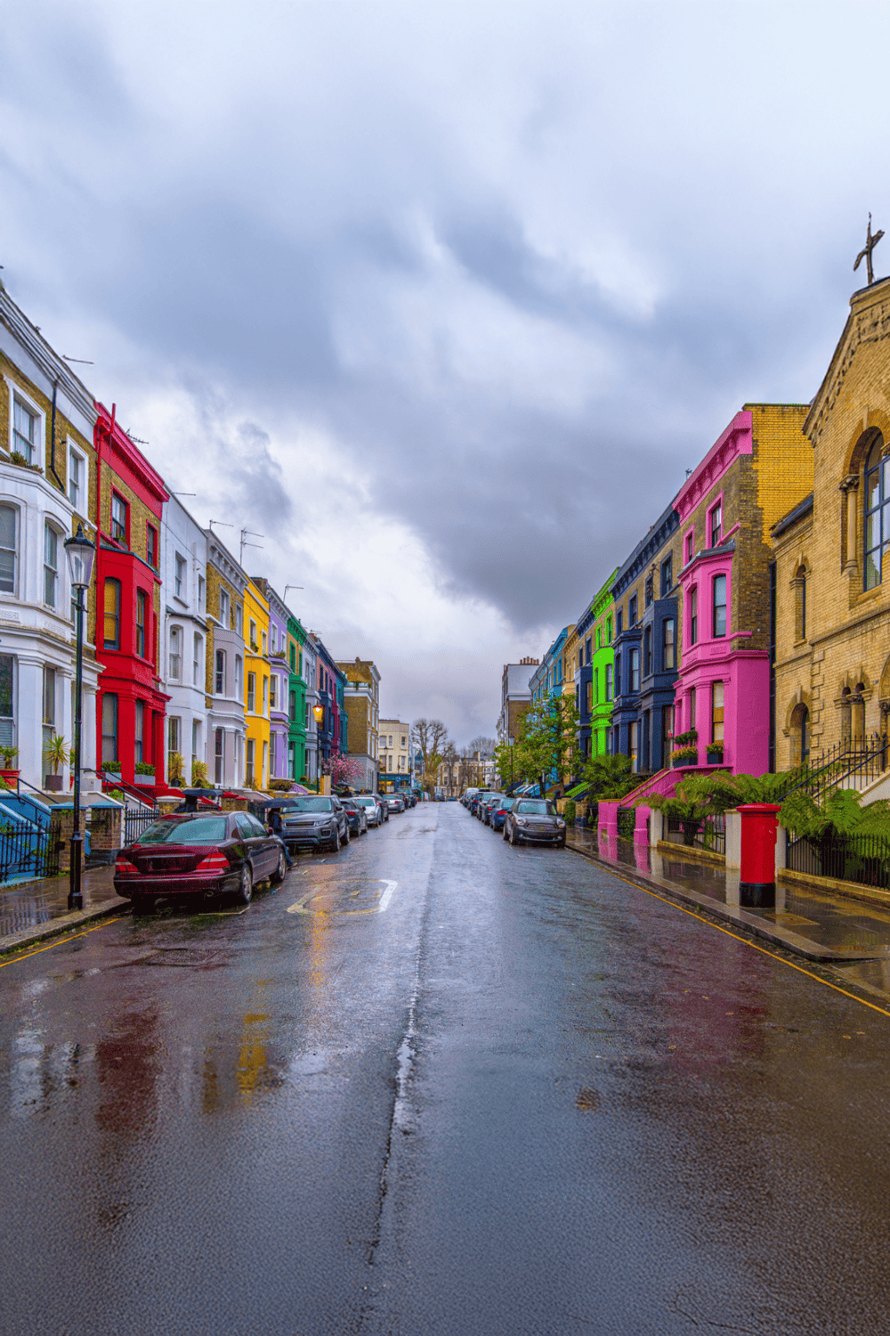 Colorful row of vibrant painted houses on a rainy street in Brixton, London.
