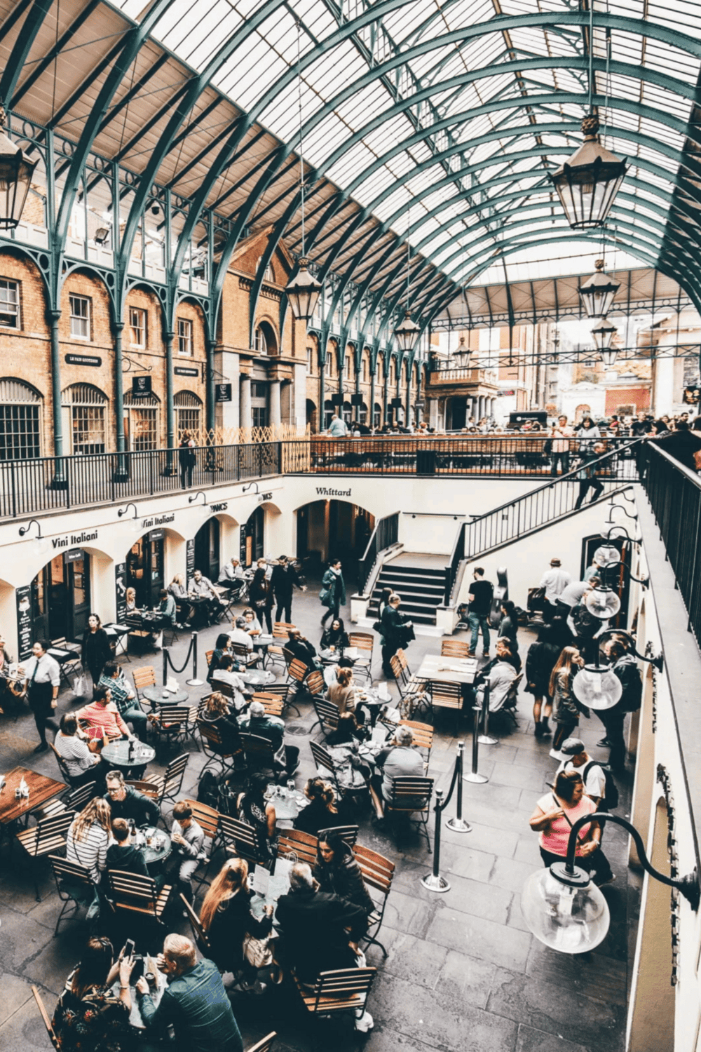 Vibrant indoor marketplace with historical architecture and bustling dining areas, ideal for food, shopping, and exploration.
