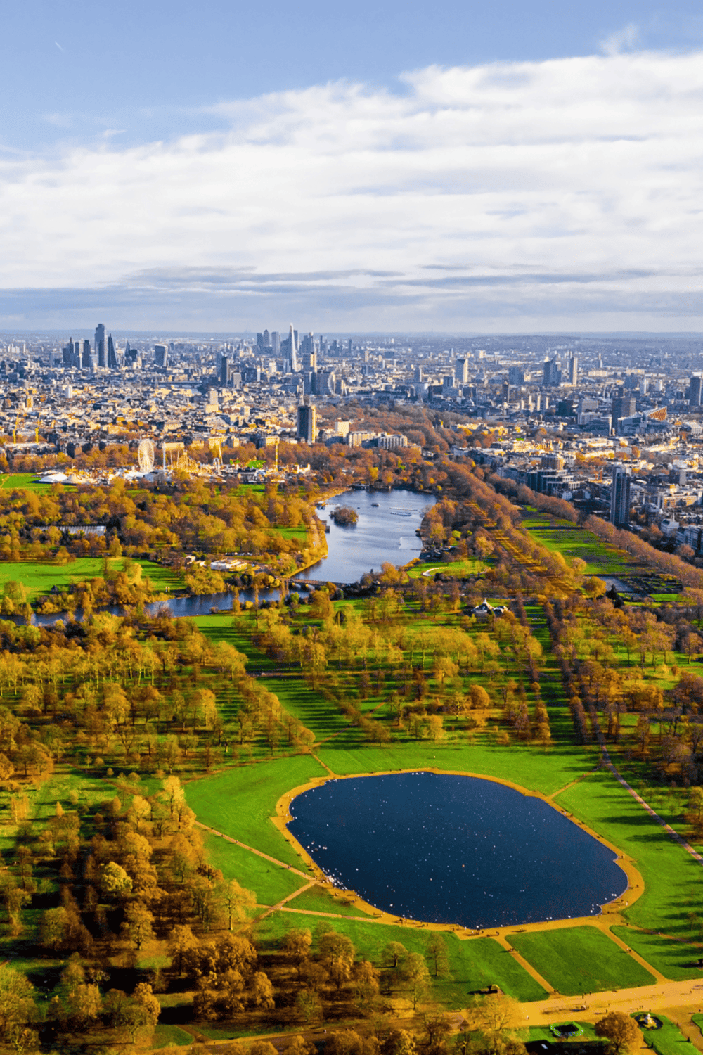 Aerial view of San Francisco Golden Gate Park and city skyline with lush greenery and water bodies.