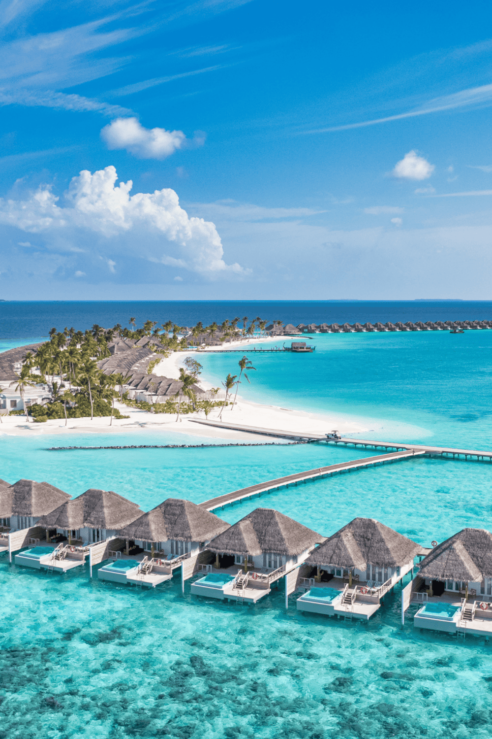 Overwater bungalows at a tropical resort with clear blue ocean waters and palm trees, perfect for vacation travel.