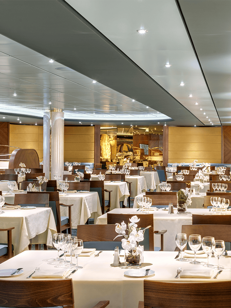 Elegant restaurant dining room with white tablecloths and floral centerpieces for fine dining experience.