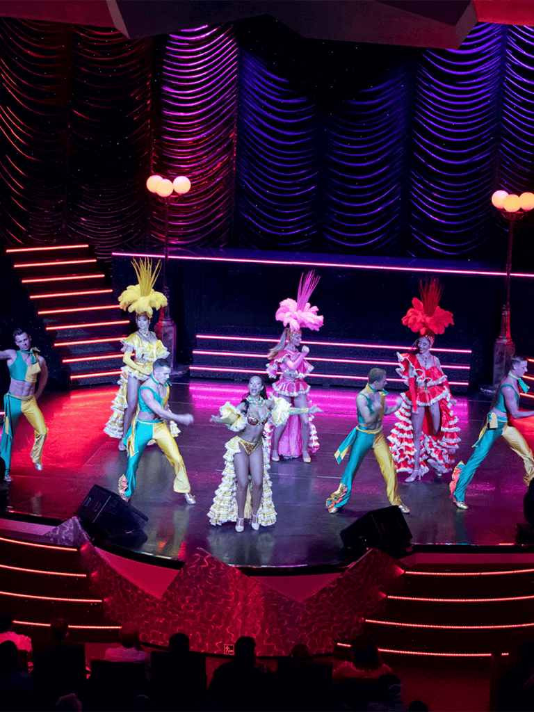 Vibrant stage performance with colorful costumes and lively dancing in a theater setting.