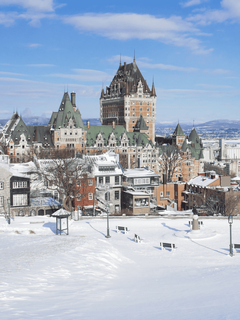 Snow-covered historic hotel with Victorian architecture in Quebec City, Canada, during winter.