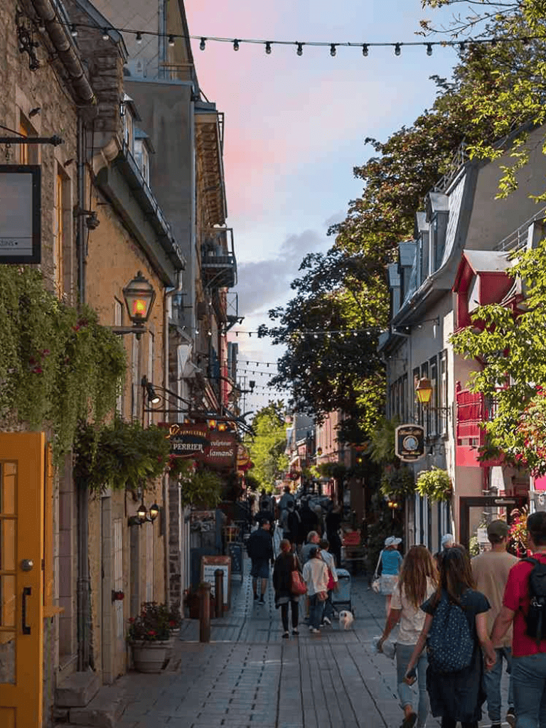 Colorful pedestrian street scene with shops and tourists in Montreal's Old Port.