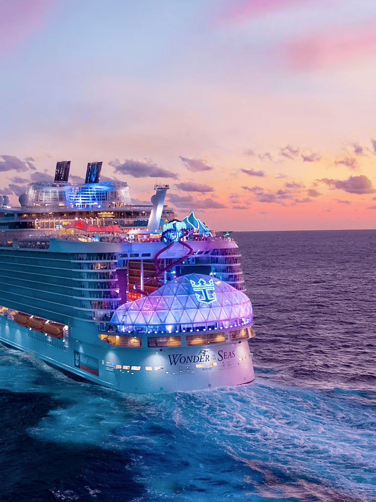 Luxury cruise ship Wonder of the Seas during sunset, showcasing vibrant lights and ocean view for memorable travel experience.