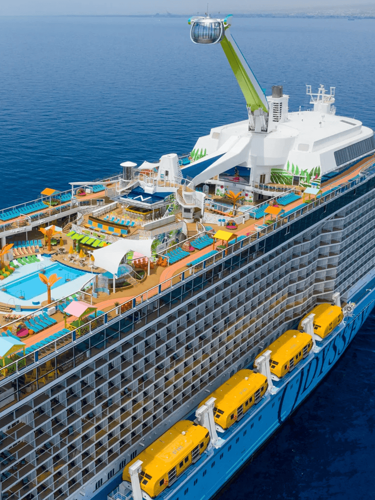 Vibrant cruise ship deck with pool, lounging areas, water slides, and scenic ocean view.