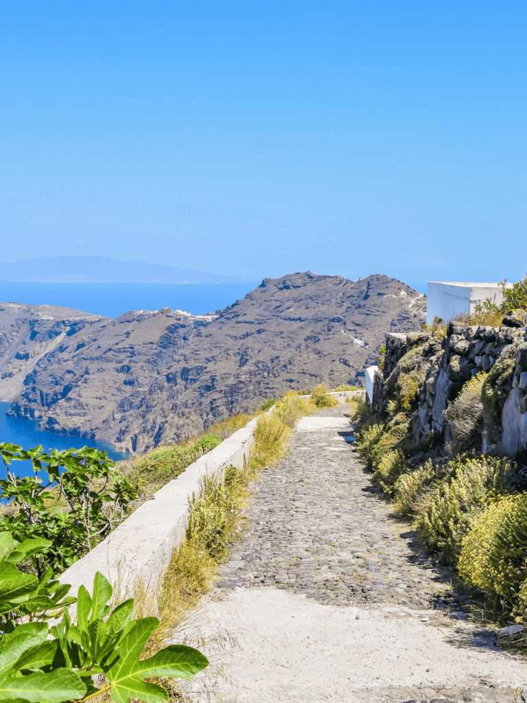 Walking path on Santorini island with scenic ocean views and rocky terrain, ideal for travel and adventure.