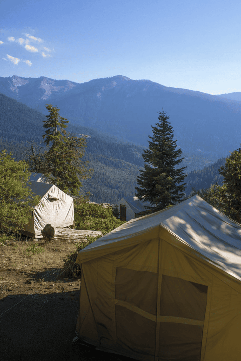 Secluded mountain camping tents with forest and mountain views, outdoor adventure, nature exploration, and wilderness experience.