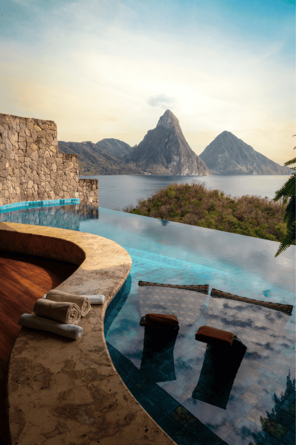 Stunning infinity pool overlooking mountains and water in tropical paradise.
