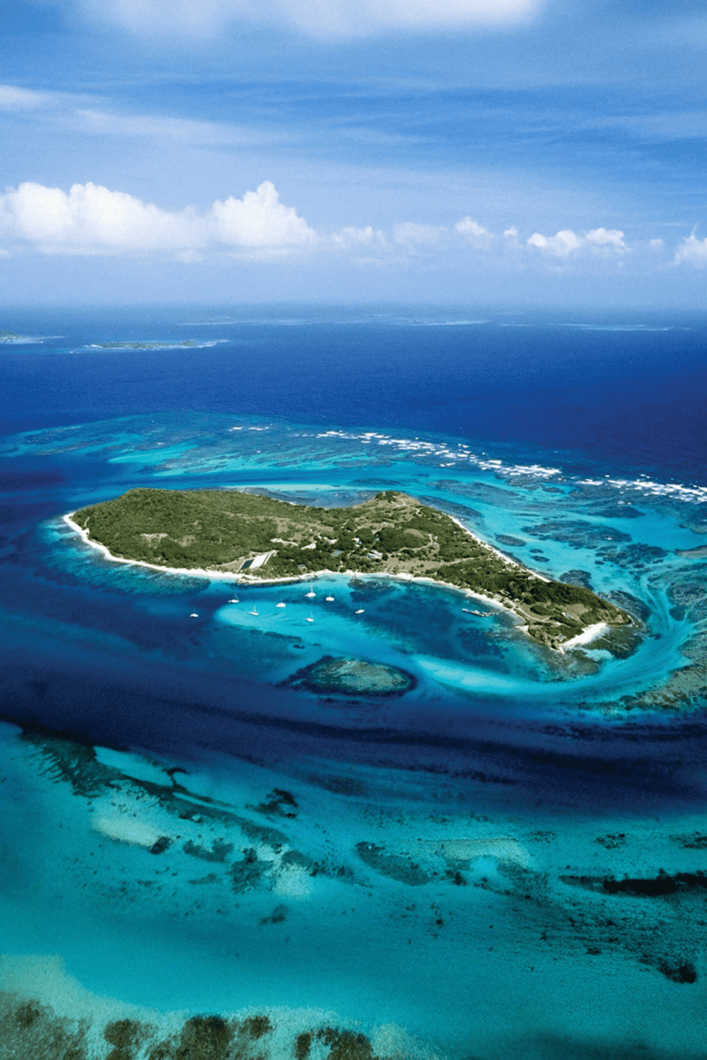 Vibrant aerial view of a tropical island with turquoise waters and coral reefs, showcasing beautiful scenic beaches and lush greenery.
