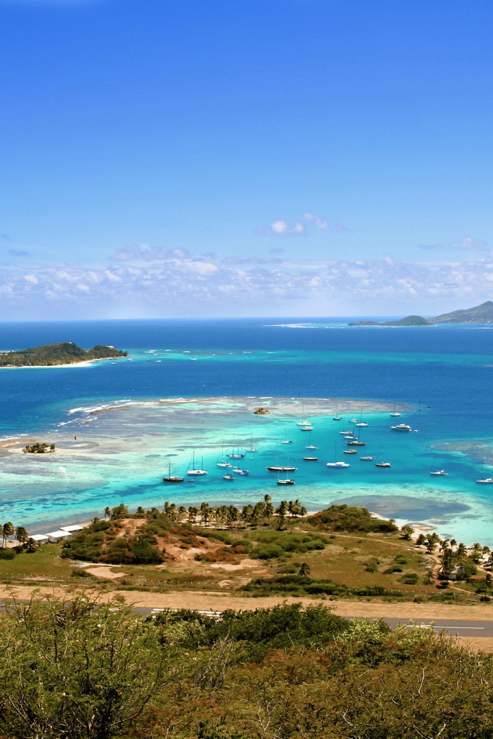 Serene tropical coastal view with boats, turquoise waters, and lush greenery, highlighting travel and adventure destinations.