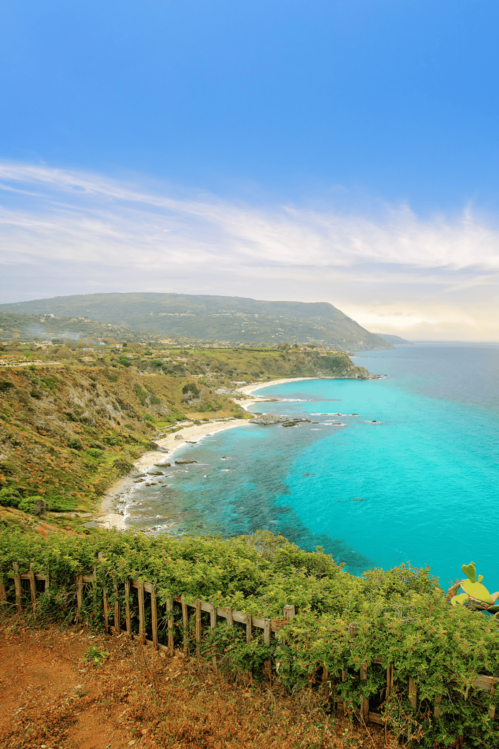 Cliffside coastal view with turquoise ocean and lush greenery, showcasing scenic travel destinations.