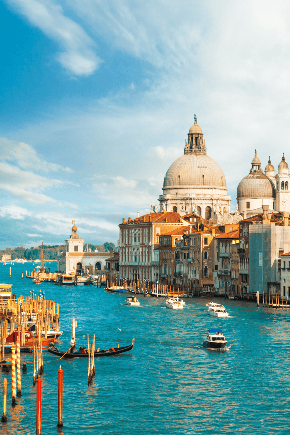 Colorful Venice canal with historic architecture and boats under blue sky, showcasing travel destinations.