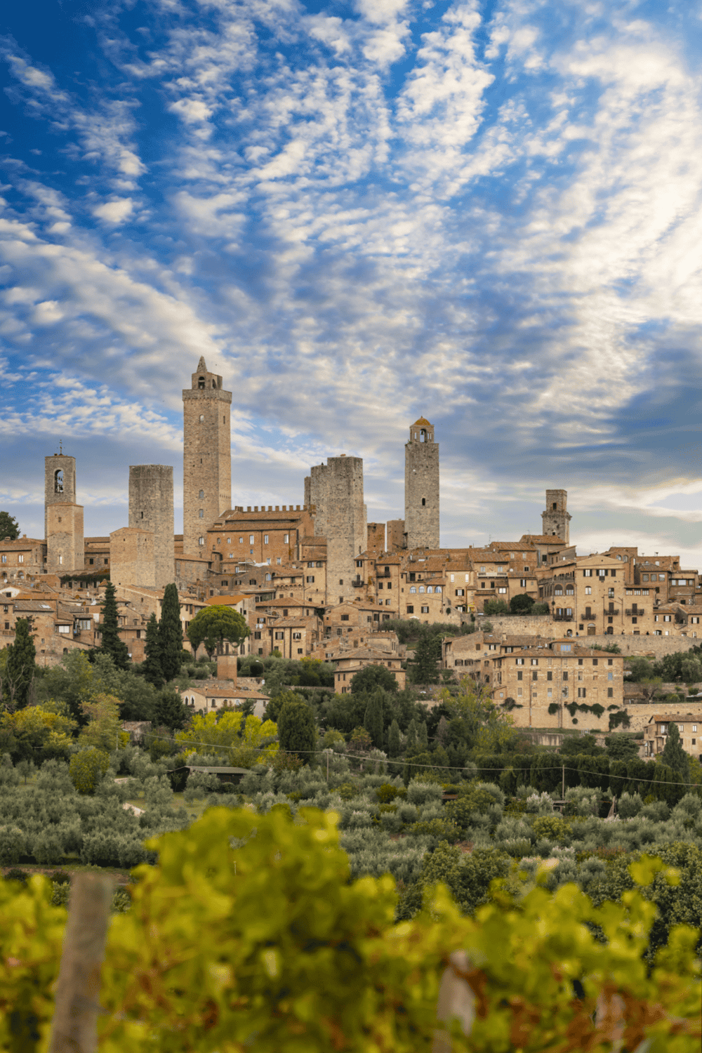Ancient medieval town of San Gimignano with towers under a cloudy sky, Italy travel destination.