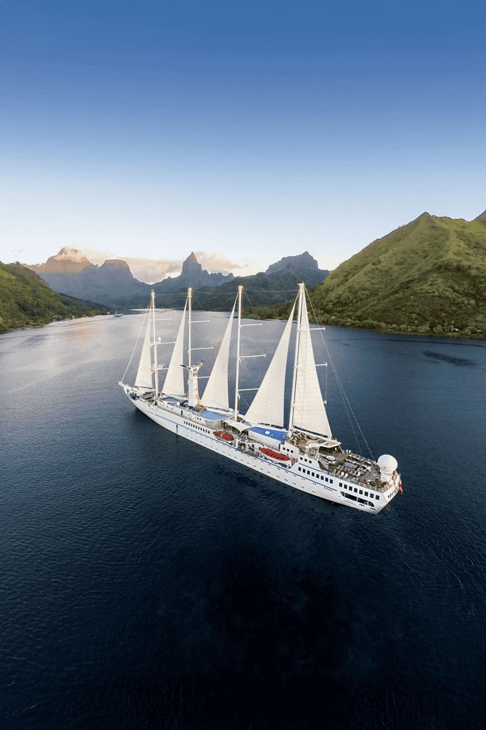 Luxurious sailing yacht cruising through lush green fjords with scenic mountain views, perfect for travel and adventure.
