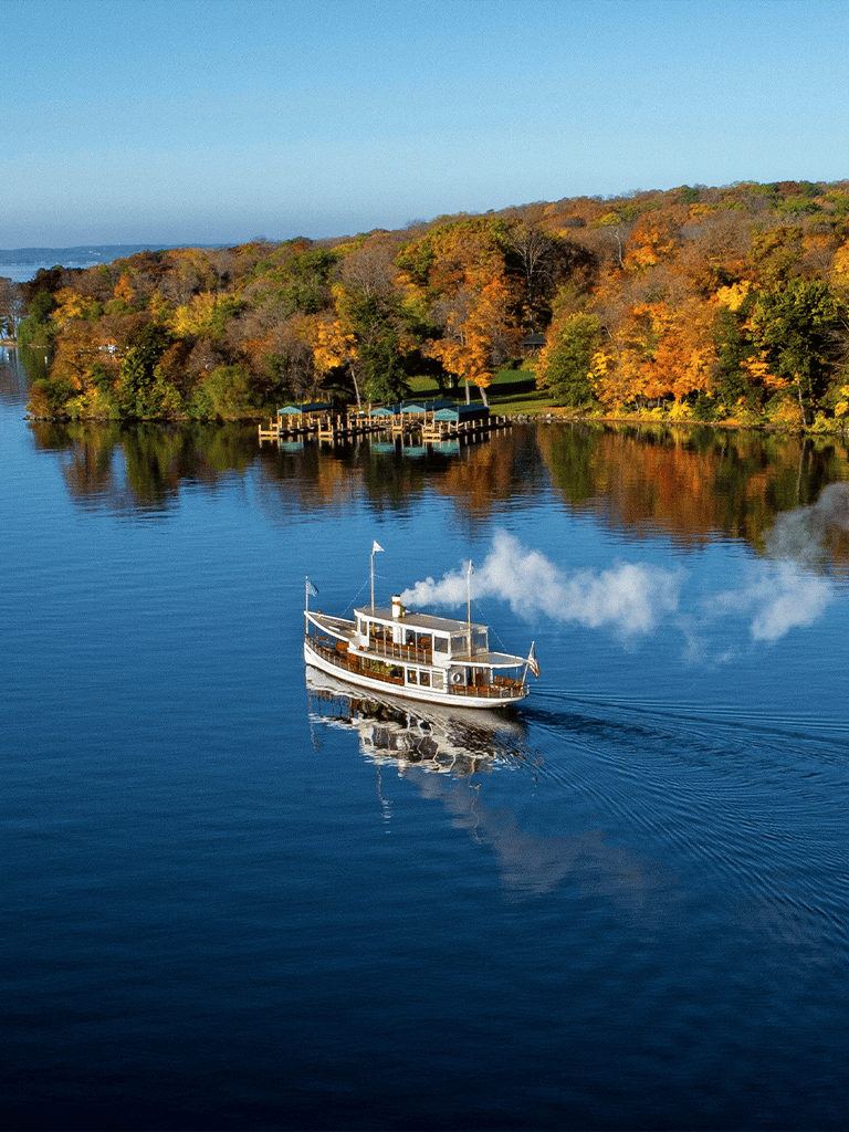 Serene boat cruise on a river surrounded by fall foliage.