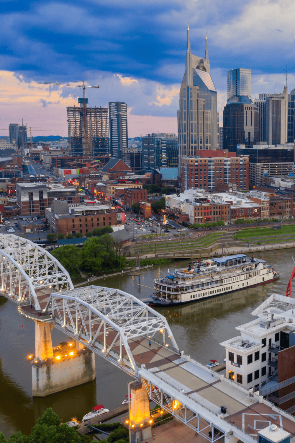 City skyline with downtown Nashville, river, and iconic bridges at dusk, showcasing vibrant urban life.