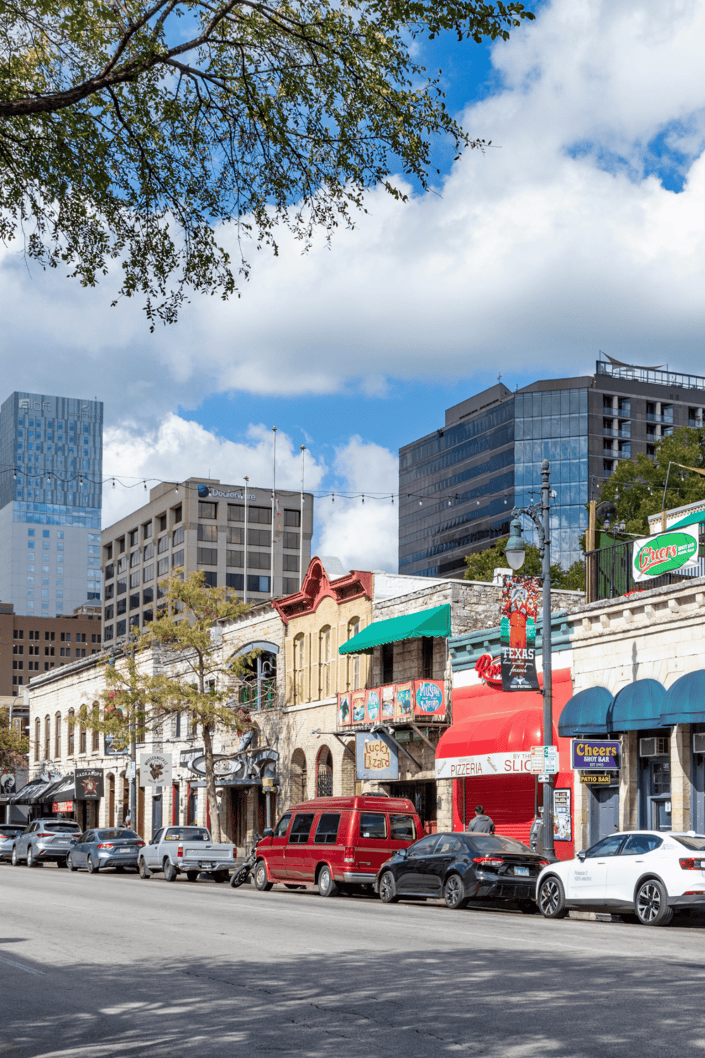 Vibrant downtown street with cafes, bars, and modern skyscrapers in the background, perfect for urban exploration and directions.