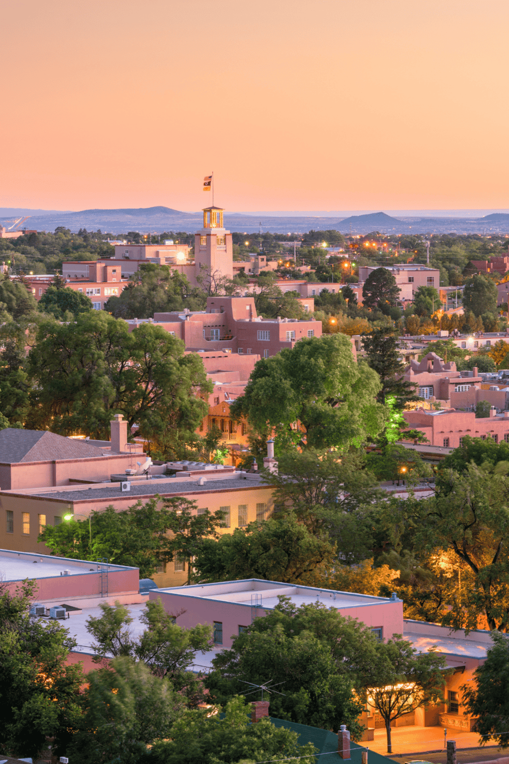 Elegant Santa Fe cityscape at sunset with adobe architecture and greenery.