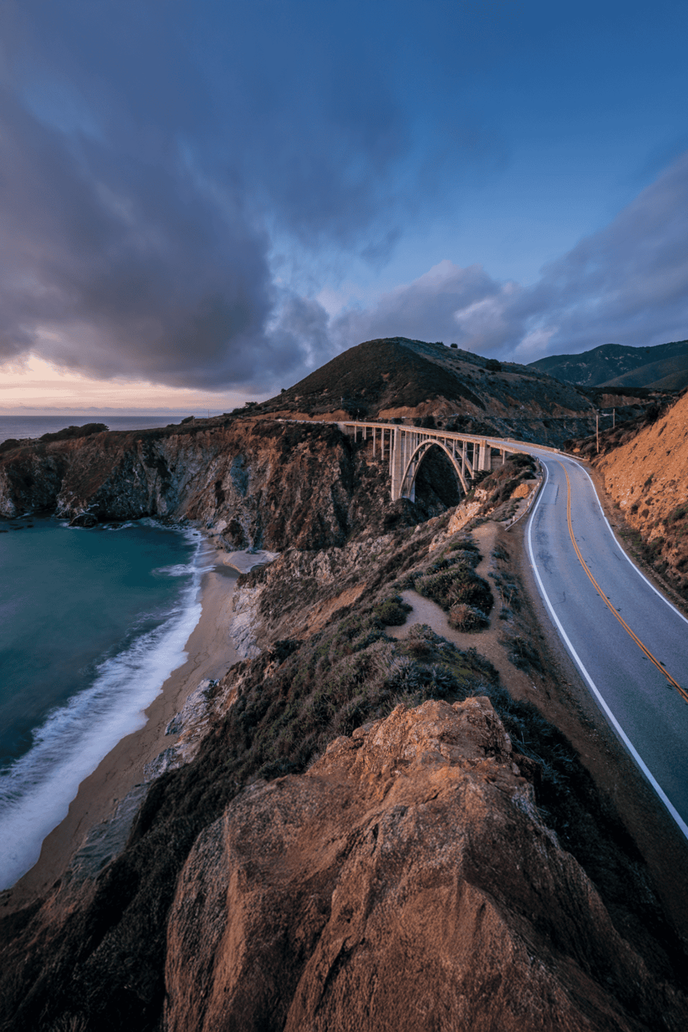 Scenic coastal highway with bridge and ocean view at sunset, ideal for road trip planning and navigation.