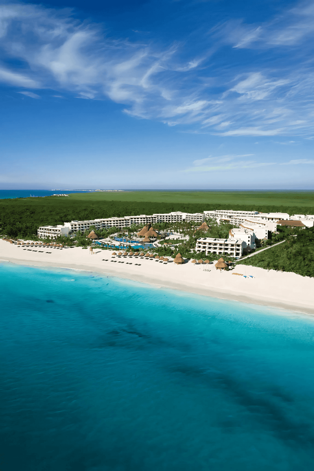Beachfront resort with white sands, ocean views, and lush greenery, ideal for relaxing vacations.
