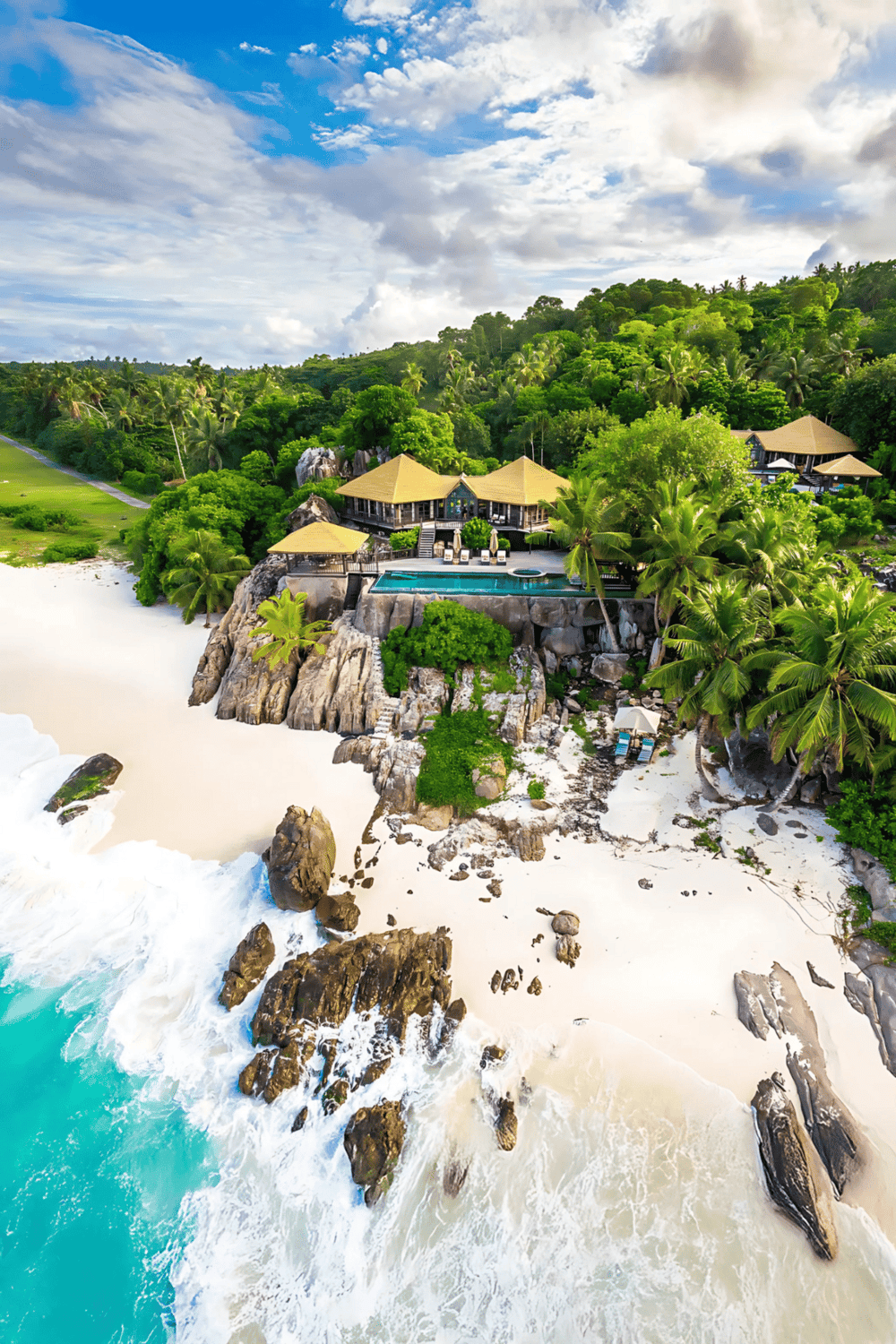 Luxurious beachfront villa with infinity pool surrounded by tropical palm trees on a pristine beach.