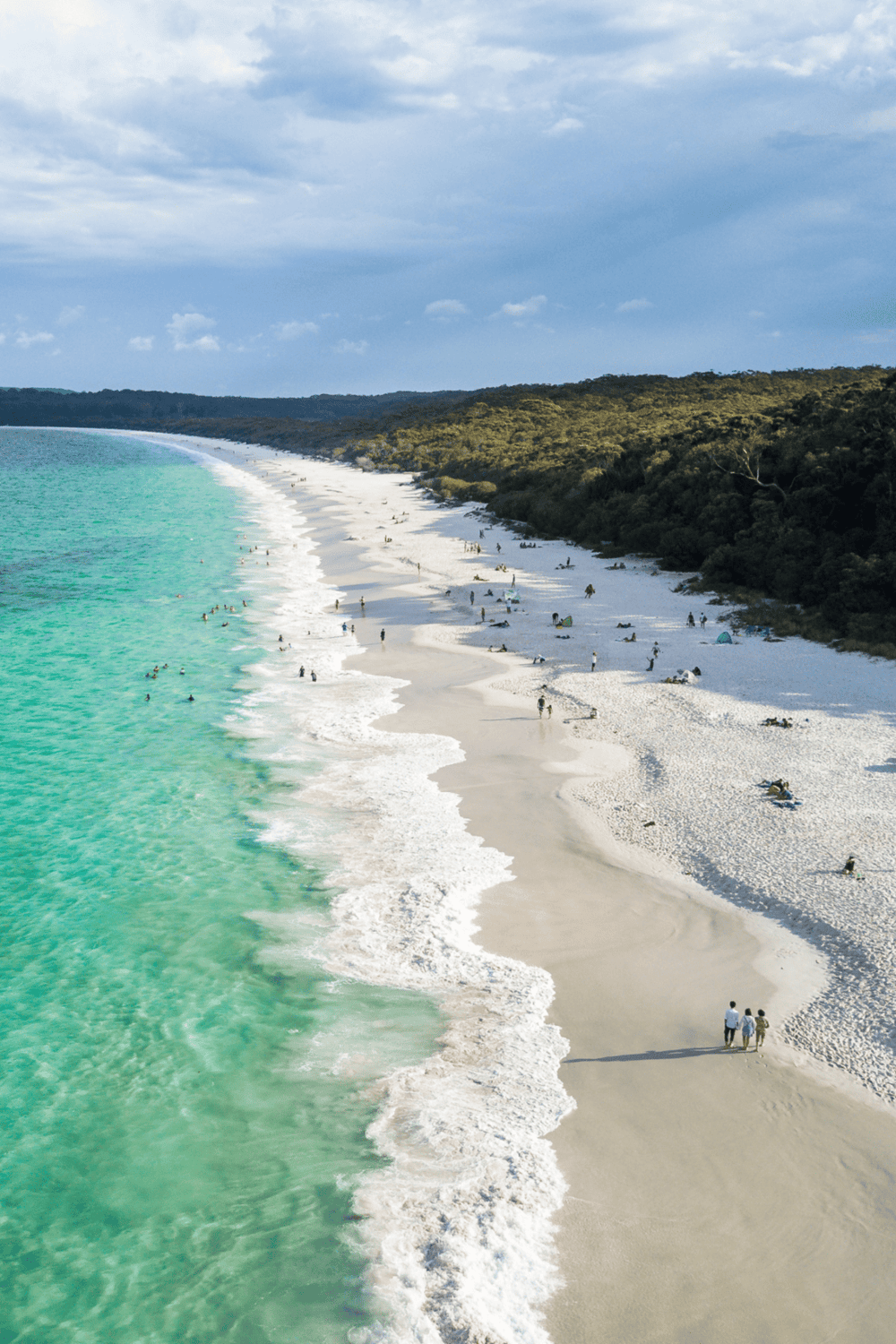 Pristine beach with turquoise waters and lush green forest, perfect for travel and vacation sightseeing.
