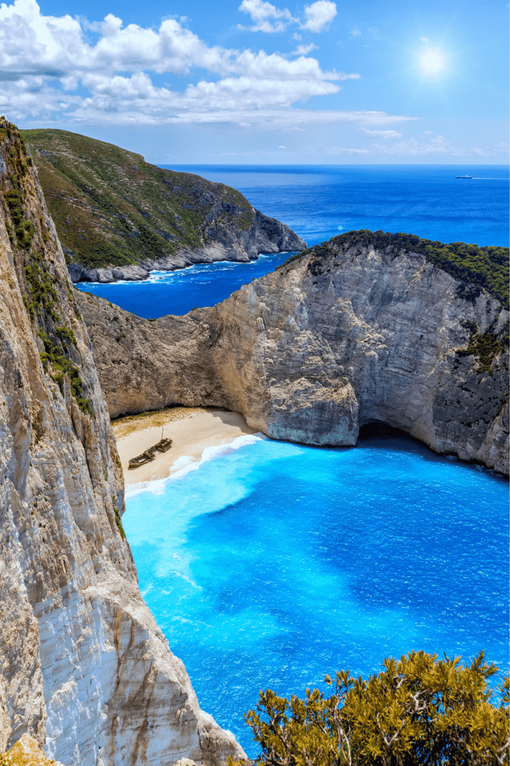 Vibrant coastal cliffside with turquoise waters and sandy beach, promoting travel and adventure.