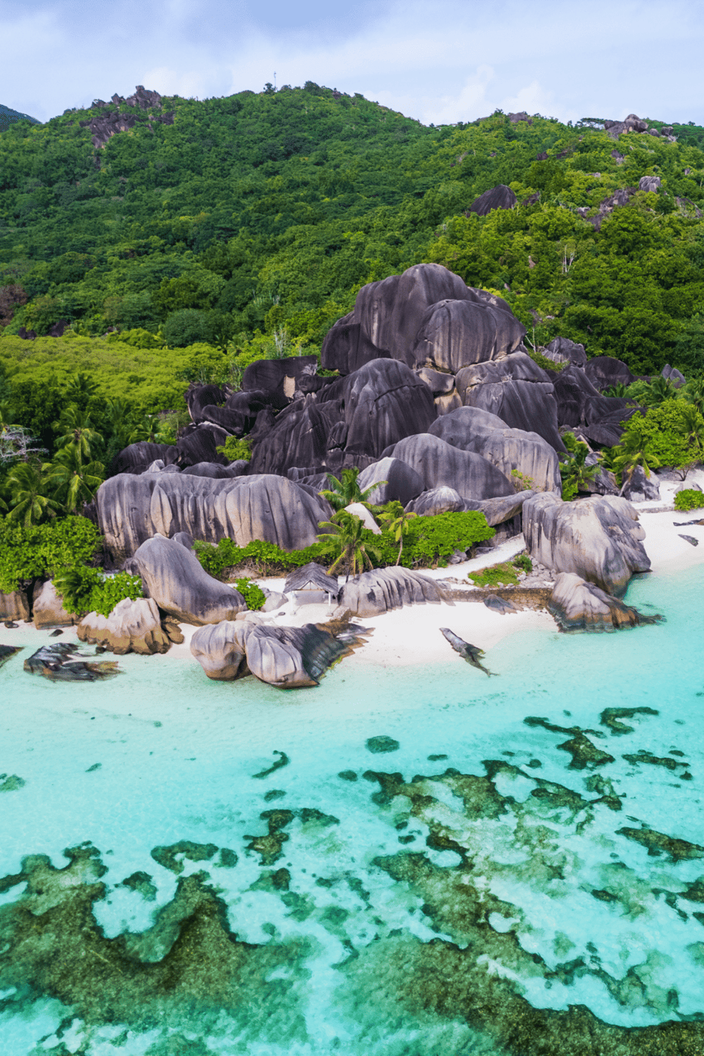 Vast tropical island scene with granite boulders, lush greenery, and turquoise waters, ideal for travel and adventure seekers.