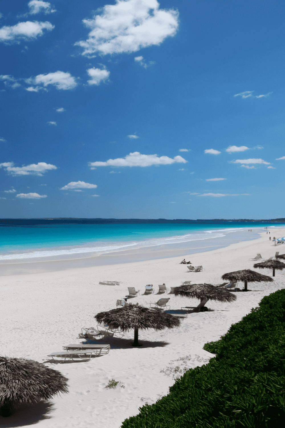 Serene beach scene with turquoise waters, white sand, and thatched umbrellas under a sunny sky. Perfect for vacation, travel, and seaside relaxation.