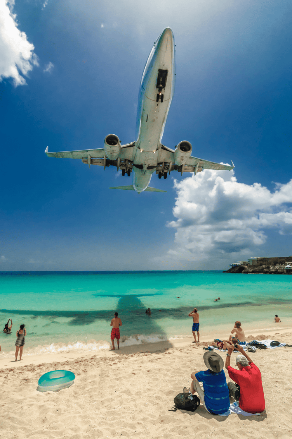 1. Airplane flying over beach with tourists, sunny sky, travel destination.